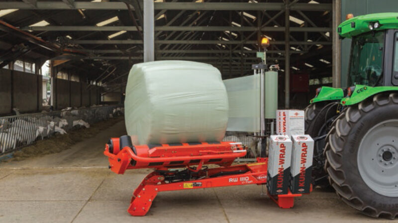 RW 1110 enrubannant une balle ronde devant une chèvrerie.