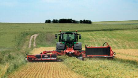 La faucheuse-conditionneuse à tapis regroupeur d'andains au travail lors du détourage d'une parcelle de ray-grass