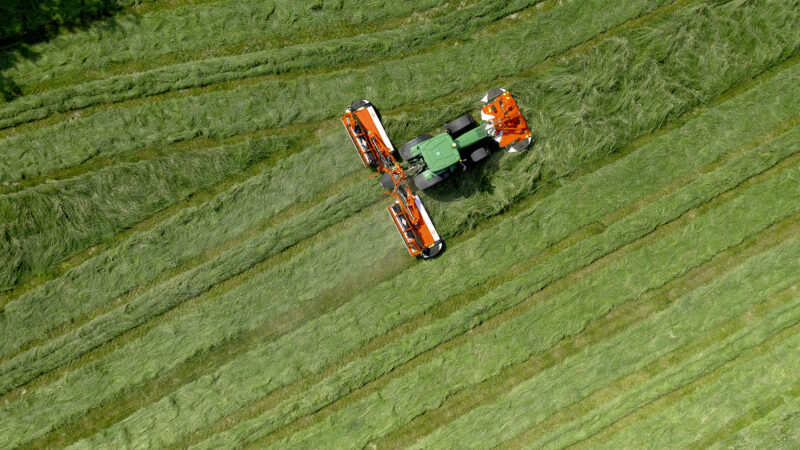 Photo de la faucheuse-conditionneuse à tapis regroupeurs d'andains FC 9330 RA au travail dans une prairie