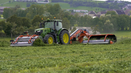 L'andaineur à tapis frontal MERGE MAXX 440 F attelé à un andaineur à tapis arrière MERGE MAXX 950 au travail dans une parcelle.