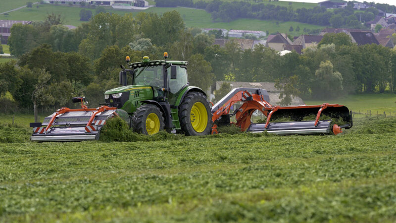 L'andaineur à tapis frontal MERGE MAXX 440 F attelé à un andaineur à tapis arrière MERGE MAXX 950 au travail dans une parcelle.