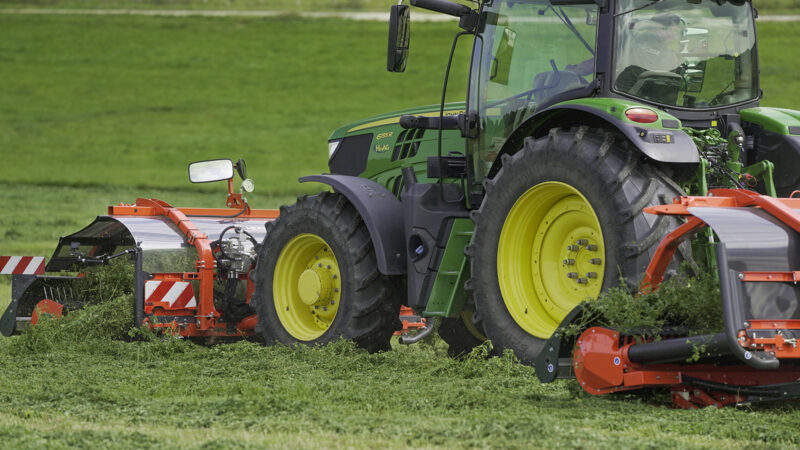 L'andaineur à tapis frontal MERGE MAXX 440 F attelé à un andaineur à tapis arrière MERGE MAXX 950 au travail dans une parcelle.
